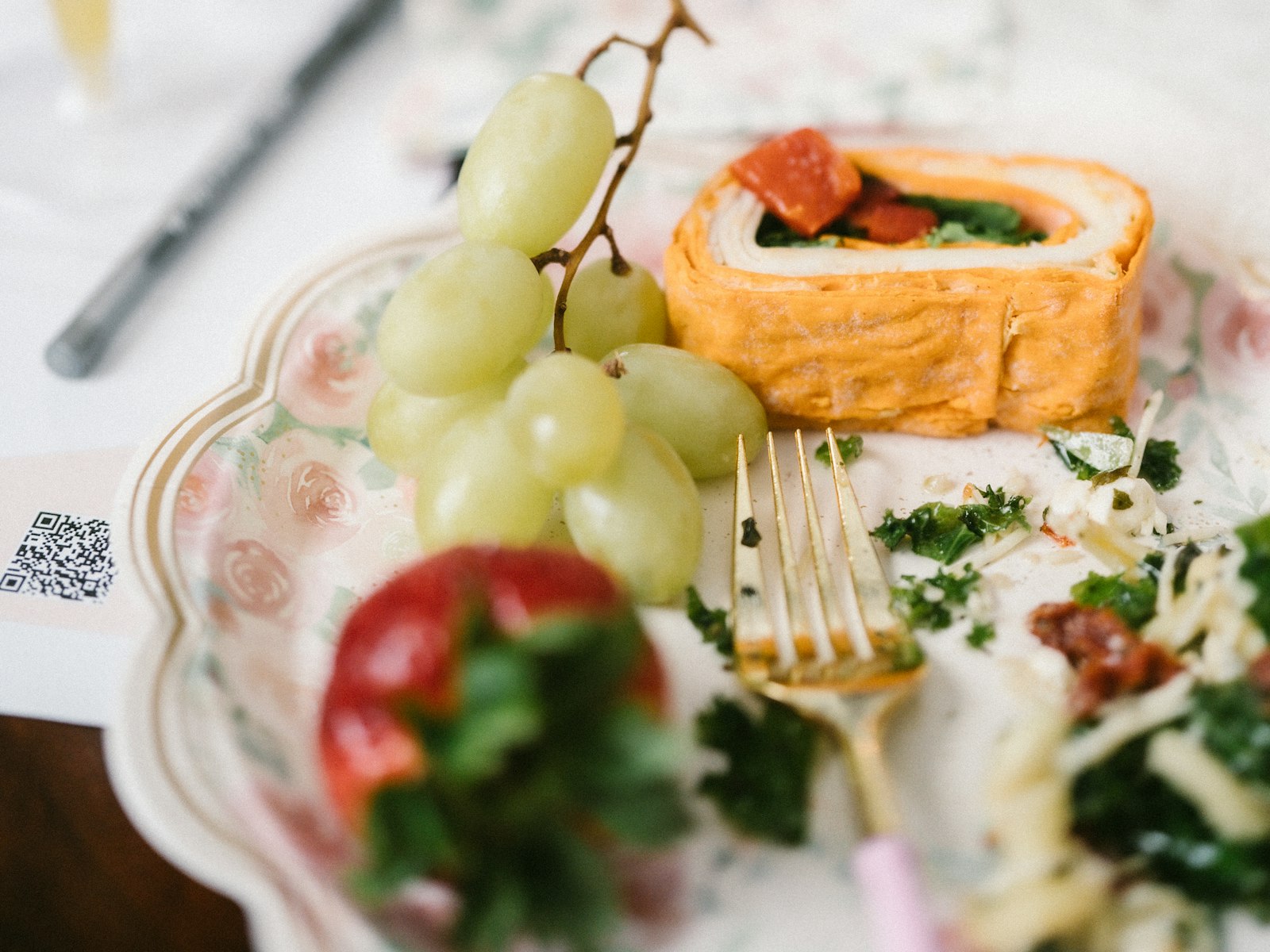 A breakfast plate with pastry and grapes on a white cloth