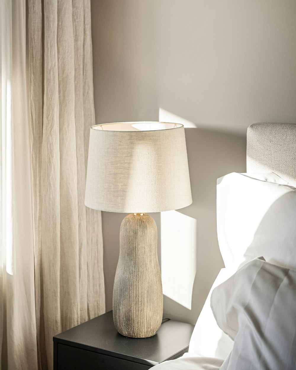 The corner of the Harbour Room with a lamp lit beside the bed